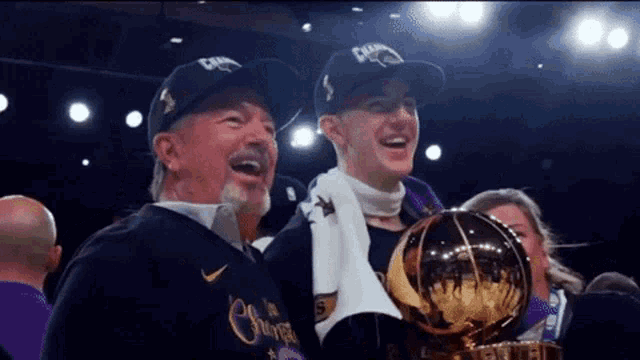 a man and a boy are holding a trophy and wearing hats that say champions