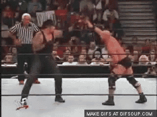 two wrestlers are fighting in a ring with a referee watching .