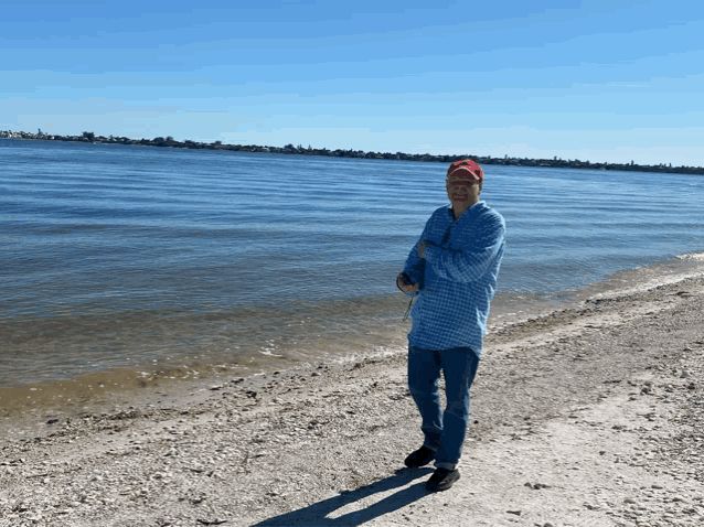 a man in a red hat is standing on a beach near the water