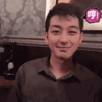 a man is smiling and looking at the camera while sitting at a table in a restaurant .