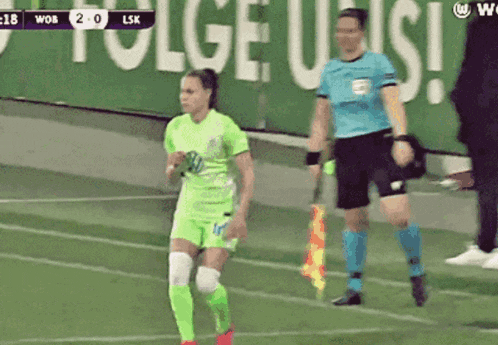 a female soccer player in a green uniform is running on a field