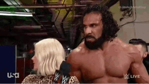 a man with a beard is talking into a microphone while standing next to a woman with a leopard print shirt .