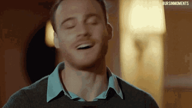 a man is laughing with his eyes closed in a close up of his face .