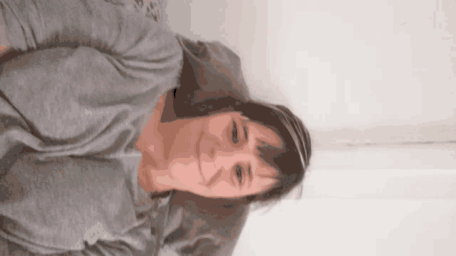 a woman in a grey shirt is smiling while laying down