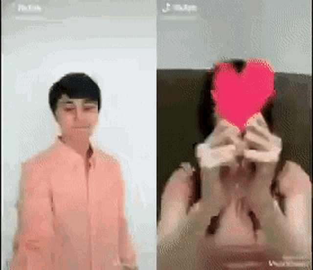 a man and a woman are standing next to each other and the woman is holding a pink heart in front of her face .
