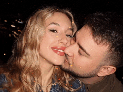 a man kissing a woman on the cheek with sparks coming out of his mouth
