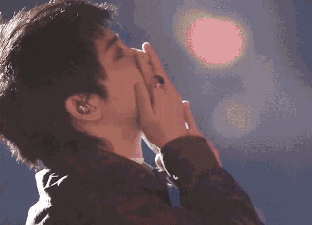 a man with a ring on his finger is covering his mouth