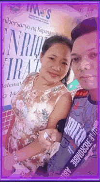 a man and a woman are posing for a picture in front of a sign that says " enrique "