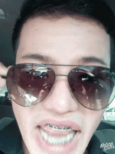 a close up of a person wearing sunglasses with motion stills written on the bottom left