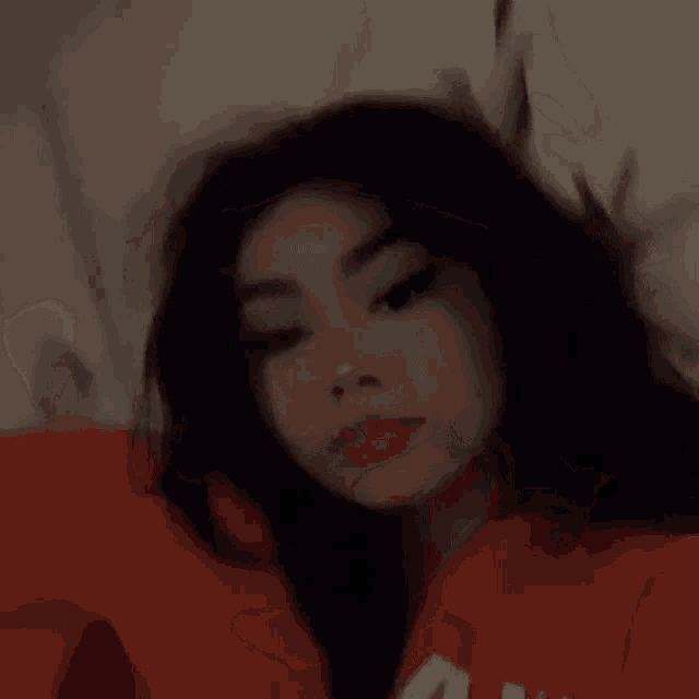 a girl is laying on a bed with her head on a pillow .