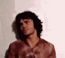 a man in a red shirt is standing in front of a wall .