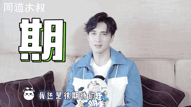 a man in a blue jacket sits on a couch with chinese writing on the bottom