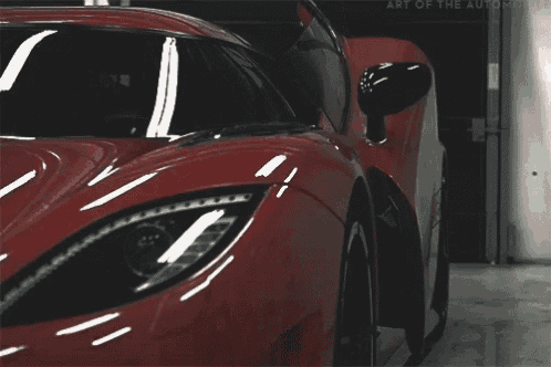 a close up of a red sports car with the words art of the auto work on the bottom