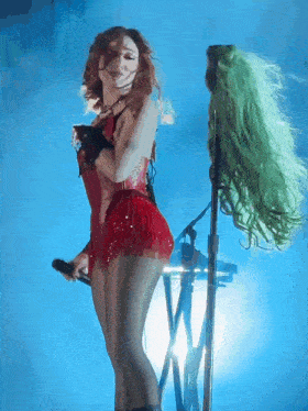 a woman in a red dress is singing into a microphone on a stage