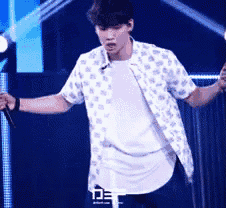 a man in a polka dot shirt is holding a microphone on a stage .