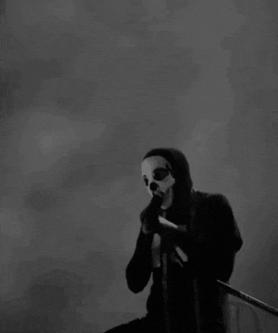 a black and white photo of a man in a mask holding a microphone .