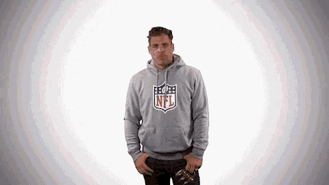 a man wearing a grey nfl hoodie holds a football