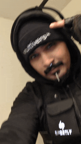 a man wearing a black jacket and a black beanie with the word monthly written on it