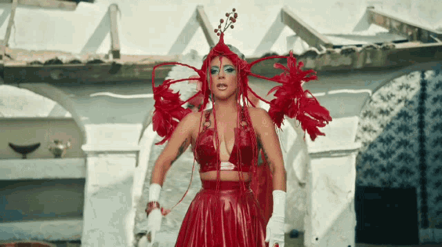 a woman wearing a red dress with feathers and a hat