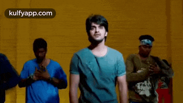 a man in a blue shirt is dancing in front of a group of men in blue shirts .