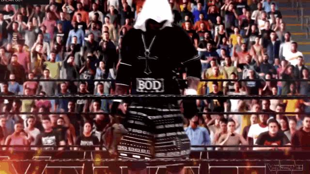 a man in a black shirt with the word bod on it stands in front of a crowd of people