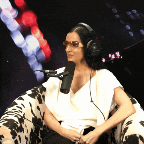 a woman wearing headphones and sunglasses sitting in front of a microphone