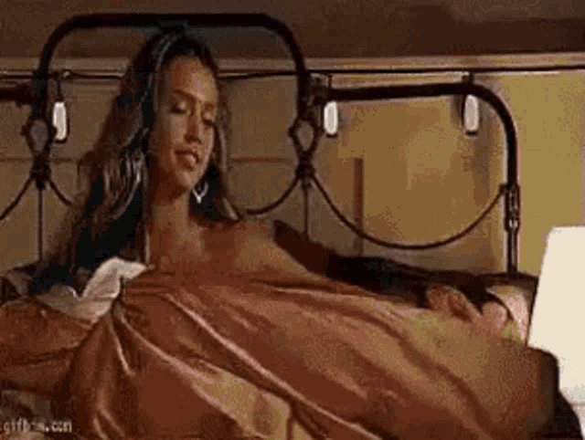 a woman is laying in bed with a man sleeping next to her and using a laptop .