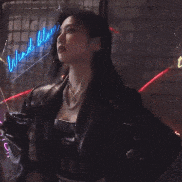 a woman in a blue leopard print jacket is standing in front of a neon sign that says blows
