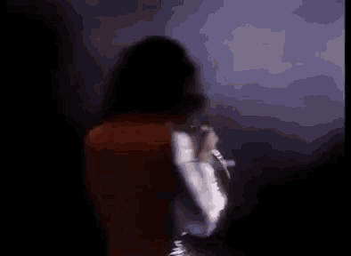 a man in a white suit is singing into a microphone on a stage .