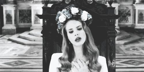 a black and white photo of a woman wearing a flower crown .