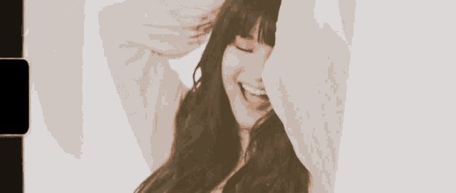 a woman with long hair is smiling and covering her face with her hand