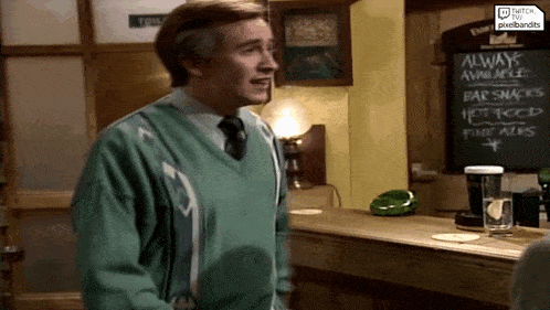 a man in a green sweater stands in front of a sign that says always available bar snacks