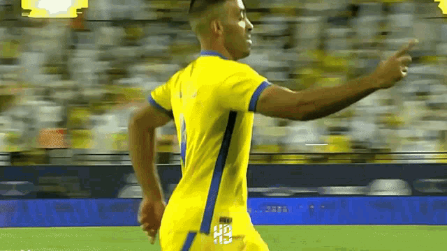 a soccer player in a yellow and blue jersey is pointing at the crowd