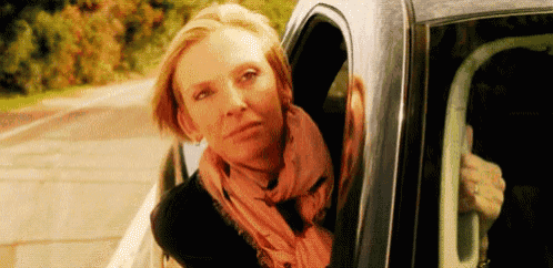 a woman is sitting in a car looking out the window .