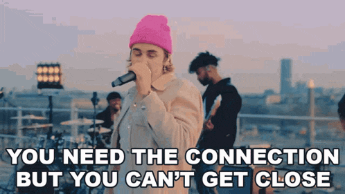 a man singing into a microphone with the words you need the connection but you can 't get close behind him .