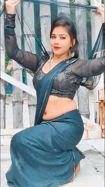 a woman in a blue saree and black blouse is kneeling down