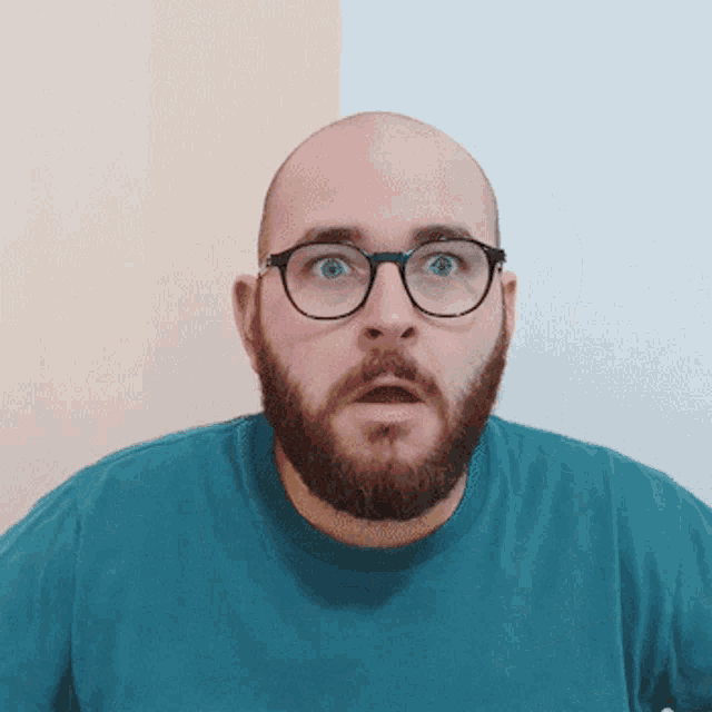a bald man with a beard wearing glasses and a blue shirt