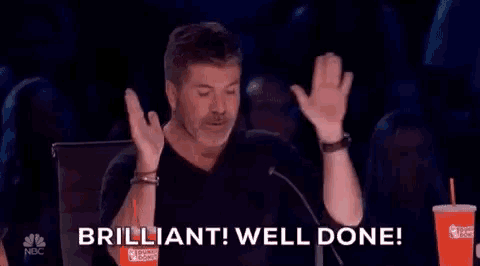 a man is sitting in front of a microphone with his hands in the air and saying `` brilliant well done '' .