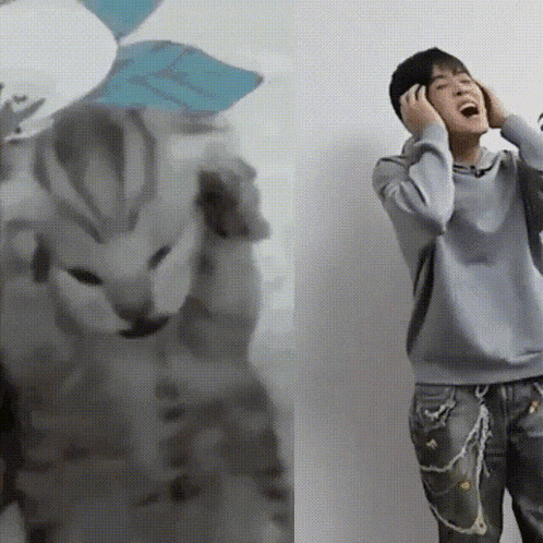 a person covering their ears with their hands while standing next to a cat