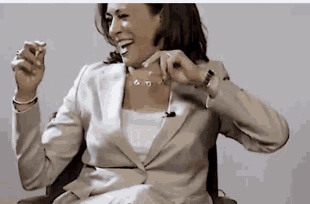 a woman in a suit is sitting in a chair and laughing while wearing a watch .