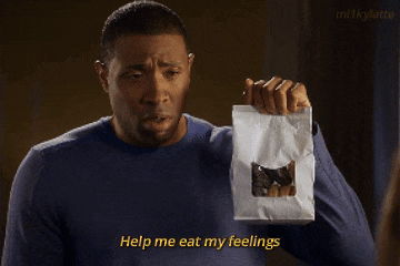 a man in a blue shirt is holding a bag that says help me eat my feelings on it