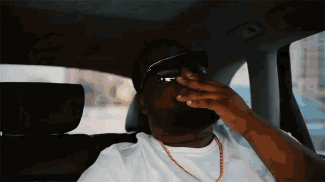 a man wearing sunglasses and a white shirt is smoking a cigarette