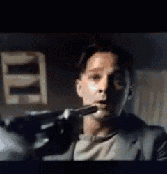 a man in a suit is holding a gun in his hand in a dark room .