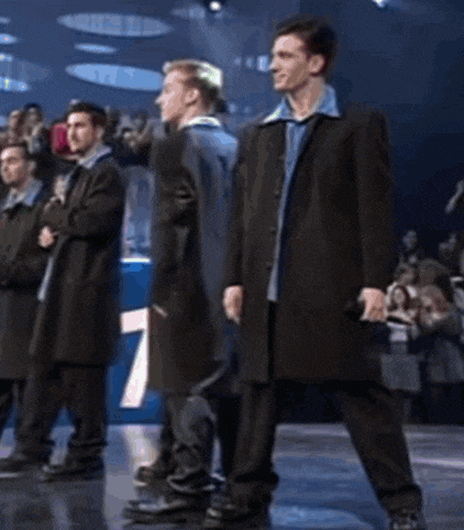 a group of men are standing in a line holding microphones