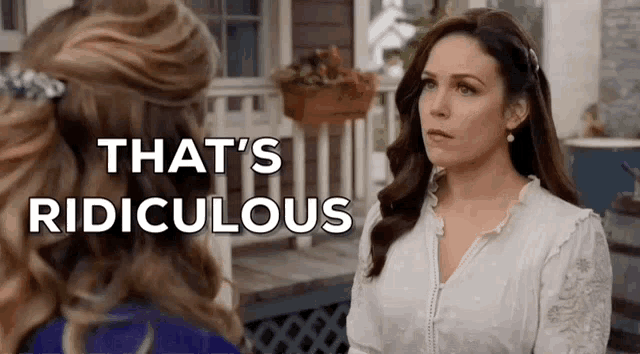 two women are standing next to each other on a porch talking to each other .