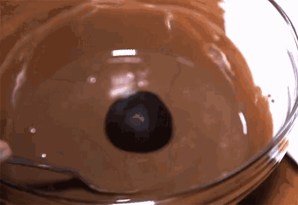 a bowl of chocolate sauce with a black ball in the middle
