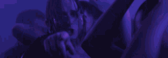 a man is holding a woman in a purple light .