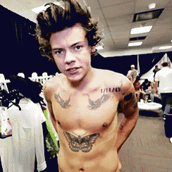 a shirtless man with a tattoo of a butterfly on his chest stands in a store