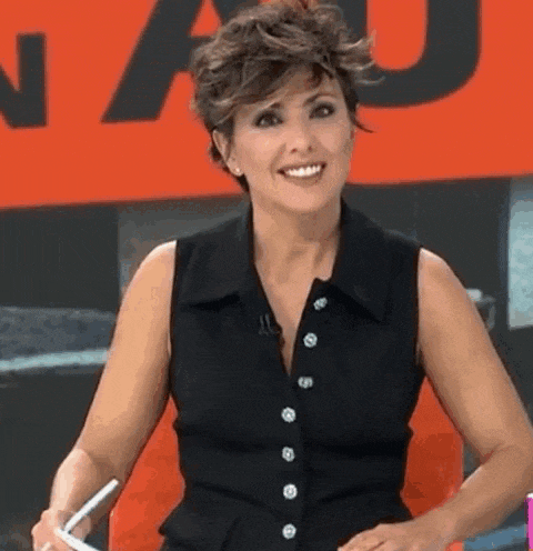 a woman in a black shirt is smiling while holding a pen .