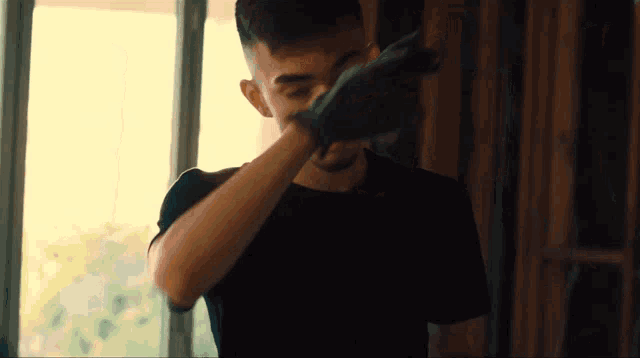 a man in a black shirt is holding a black object in his hand